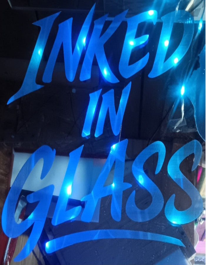 Custom mirror with 'INKED IN GLASS' engraved in the back and blue light glowing through